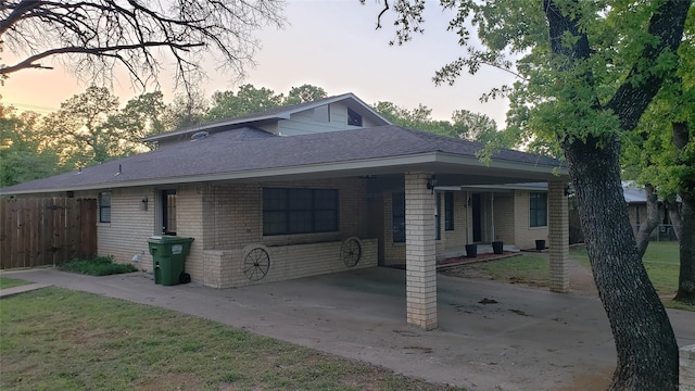 703 San Jacinto St, Mineral Wells, TX 76067 - view of front of house with brick siding, fence, a carport, roof with shingles, and driveway