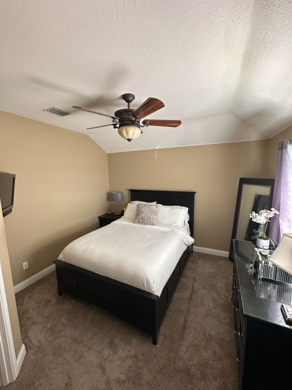 carpeted bedroom with vaulted ceiling, ceiling fan, and a textured ceiling