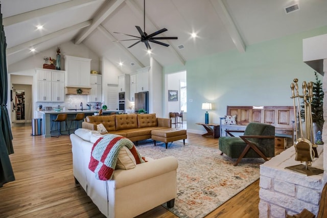 living room with sink, light hardwood / wood-style flooring, and beamed ceiling