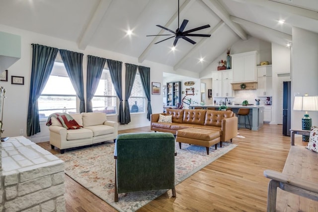 living room with beamed ceiling, ceiling fan, high vaulted ceiling, and light hardwood / wood-style floors