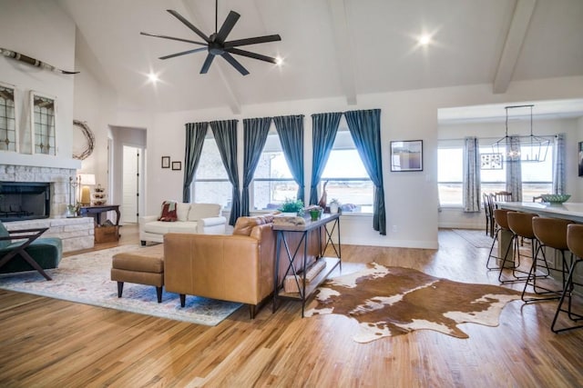 living room with beamed ceiling, high vaulted ceiling, a fireplace, and light hardwood / wood-style flooring