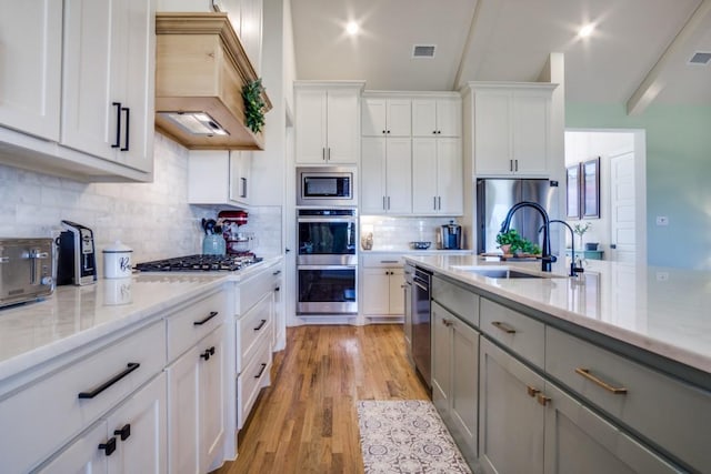 kitchen with gray cabinets, appliances with stainless steel finishes, sink, white cabinets, and custom exhaust hood