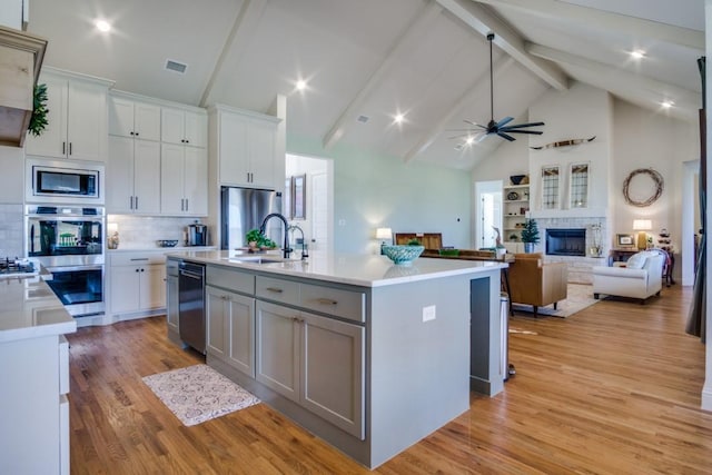 kitchen featuring white cabinetry, appliances with stainless steel finishes, sink, and a center island with sink