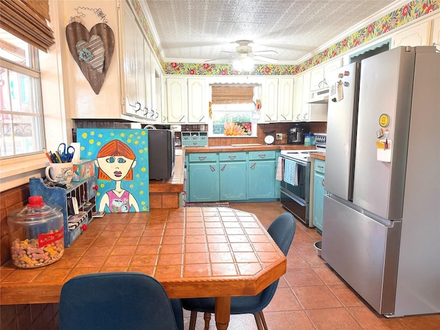 kitchen featuring light tile patterned floors, blue cabinetry, stainless steel refrigerator, range with electric cooktop, and white cabinets