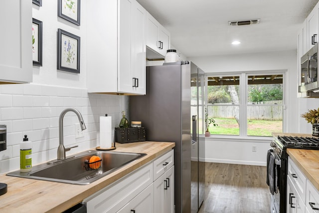 kitchen featuring sink, butcher block countertops, range with gas cooktop, white cabinetry, and light hardwood / wood-style flooring