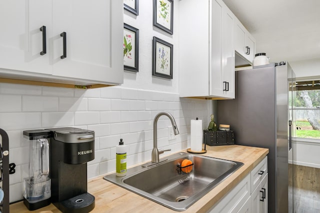 kitchen featuring wooden counters, sink, white cabinets, and backsplash