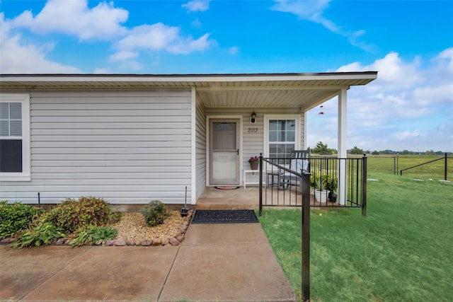 entrance to property featuring a porch and a yard