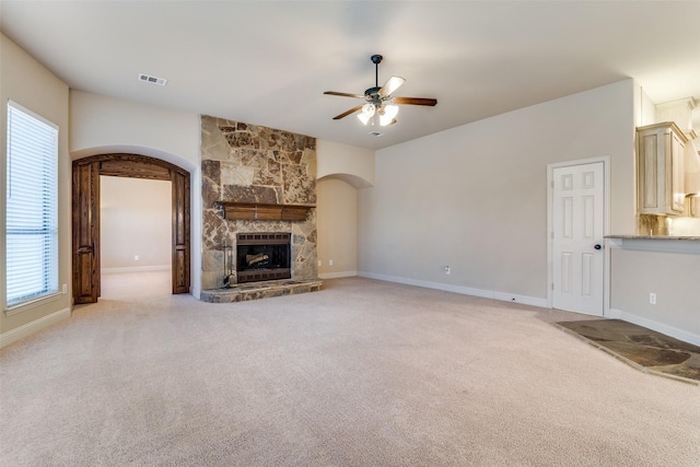 2605 Waterstone Ln, Rockwall, TX 75032 - unfurnished living room featuring arched walkways, ceiling fan, light colored carpet, and a stone fireplace