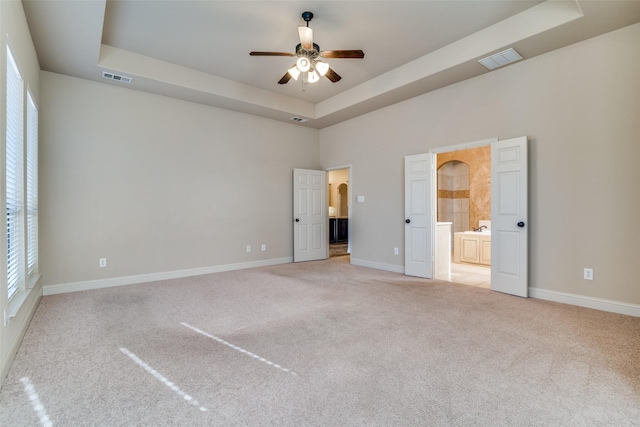 2605 Waterstone Ln, Rockwall, TX 75032 - unfurnished bedroom featuring a tray ceiling, light carpet, baseboards, and ensuite bathroom
