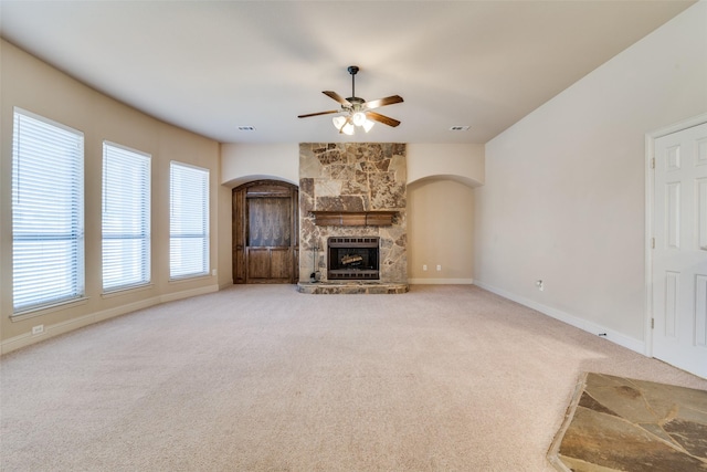 2605 Waterstone Ln, Rockwall, TX 75032 - unfurnished living room with arched walkways, carpet flooring, a ceiling fan, a fireplace, and baseboards