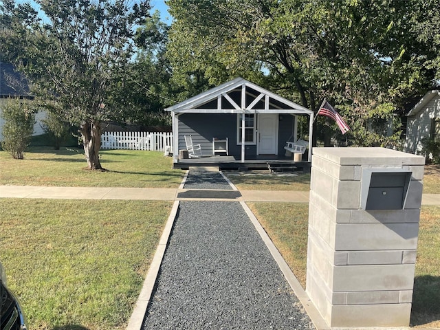 view of front of home with covered porch, a front yard, and fence