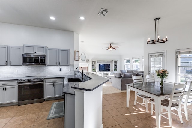 kitchen featuring appliances with stainless steel finishes, sink, backsplash, hanging light fixtures, and light tile patterned floors