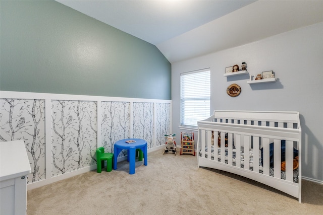 bedroom featuring lofted ceiling, a crib, and carpet floors