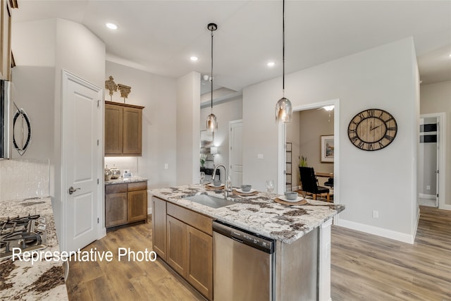 kitchen featuring appliances with stainless steel finishes, sink, hanging light fixtures, and light wood-type flooring