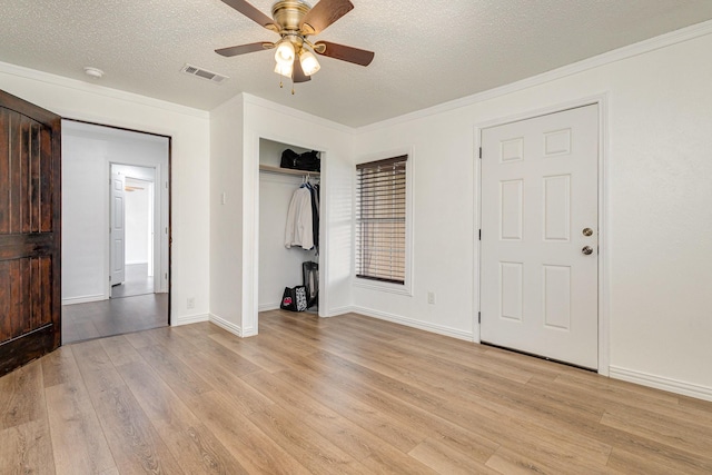 unfurnished bedroom with ornamental molding, a textured ceiling, and light wood-type flooring