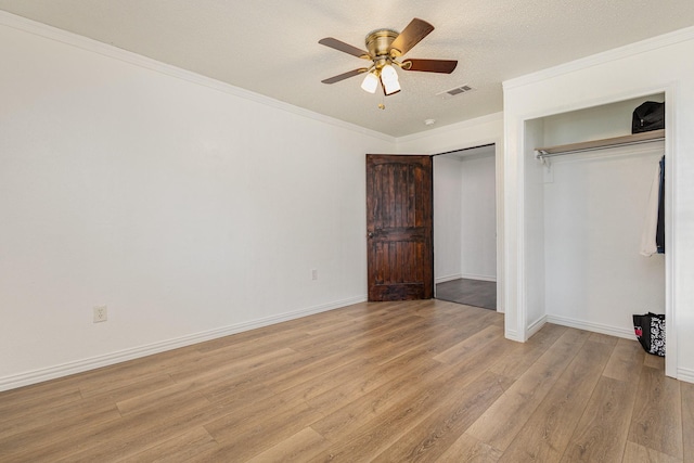 unfurnished bedroom featuring ornamental molding, ceiling fan, light hardwood / wood-style floors, a textured ceiling, and a closet