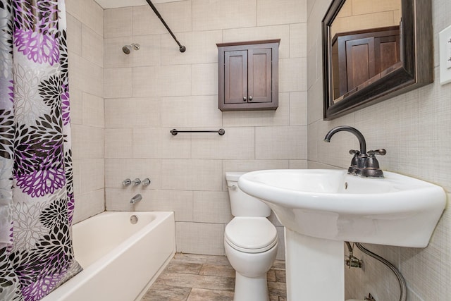 bathroom with toilet, shower / tub combo, and tile walls