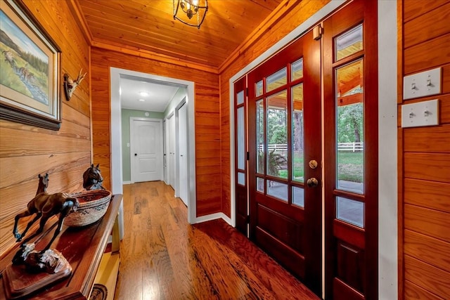 entryway with hardwood / wood-style flooring, wood ceiling, and wooden walls