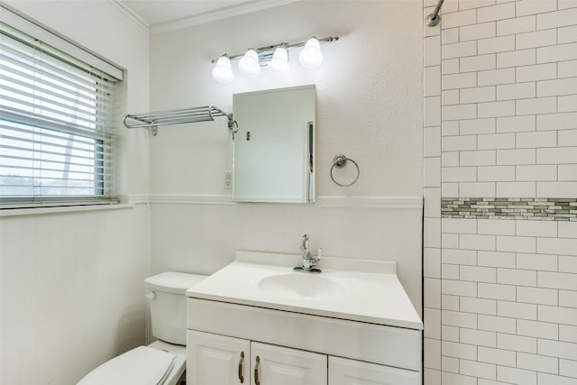 bathroom featuring ornamental molding, vanity, toilet, and a tile shower