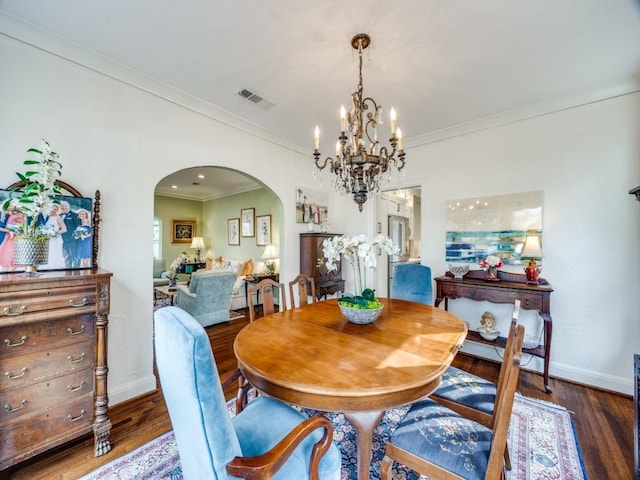 dining room with dark wood-type flooring, crown molding, and an inviting chandelier