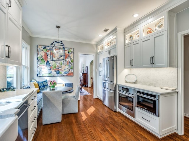 kitchen featuring crown molding, dark wood-type flooring, white cabinetry, stainless steel appliances, and decorative light fixtures