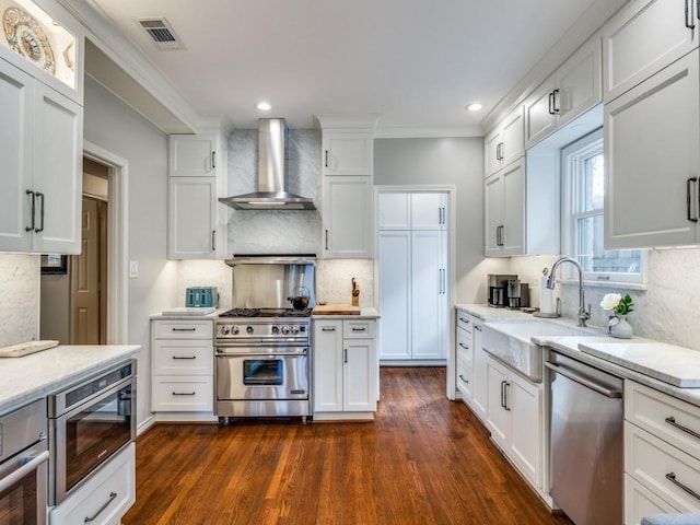 kitchen featuring white cabinetry, sink, dark hardwood / wood-style flooring, stainless steel appliances, and wall chimney range hood