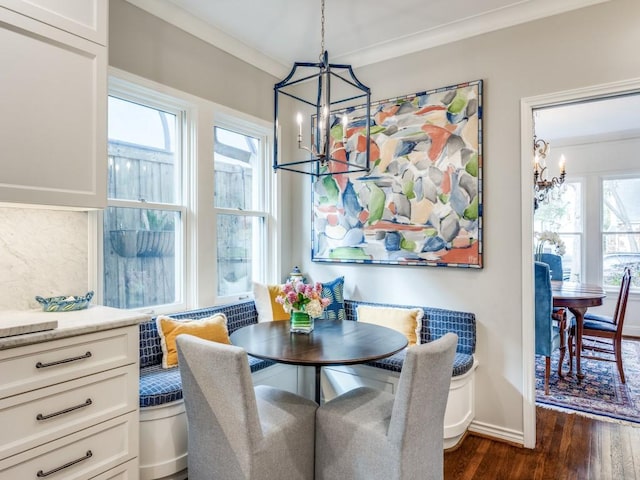 dining room with breakfast area, dark wood-type flooring, ornamental molding, and a chandelier