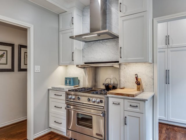 kitchen featuring white cabinetry, high end stove, dark hardwood / wood-style floors, decorative backsplash, and wall chimney range hood