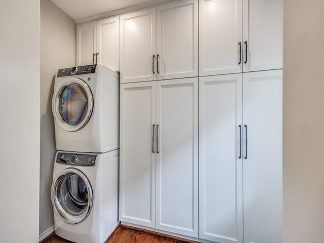 laundry room featuring stacked washer / dryer and cabinets