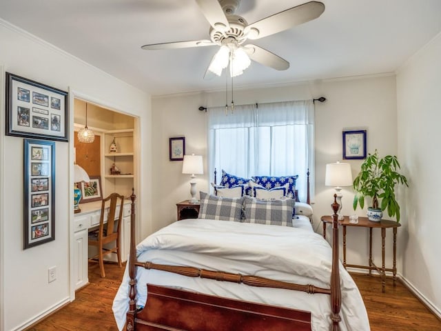 bedroom with dark hardwood / wood-style flooring, built in desk, ornamental molding, and ceiling fan