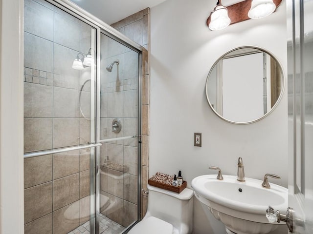 bathroom with a shower with door, sink, and toilet