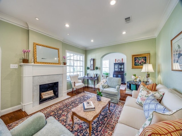 living room featuring a high end fireplace, ornamental molding, and wood-type flooring