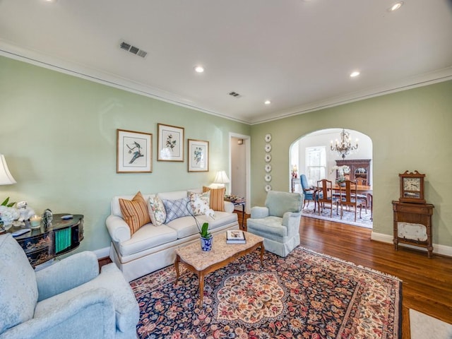 living room featuring crown molding, hardwood / wood-style flooring, and an inviting chandelier