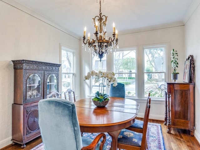 dining area featuring hardwood / wood-style flooring, crown molding, a wealth of natural light, and a notable chandelier