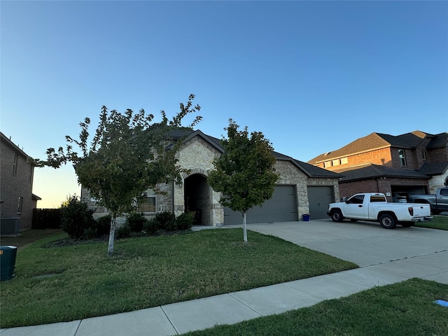 view of front of home with a yard, central AC unit, and a garage