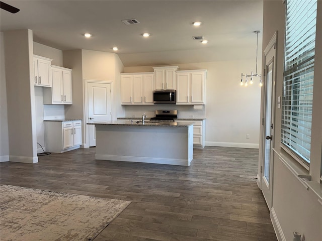 kitchen with dark hardwood / wood-style floors, a kitchen island with sink, white cabinets, and stainless steel appliances