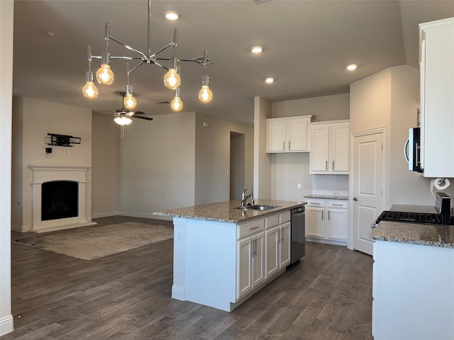 kitchen with sink, stone counters, white cabinetry, stainless steel appliances, and an island with sink