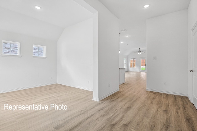 unfurnished room featuring lofted ceiling, plenty of natural light, and light wood-type flooring