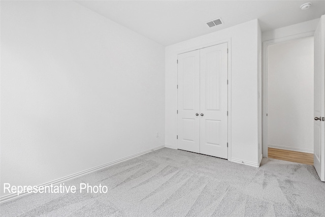 unfurnished bedroom featuring light carpet and a closet