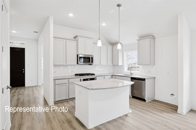 kitchen featuring sink, appliances with stainless steel finishes, decorative backsplash, a kitchen island, and decorative light fixtures