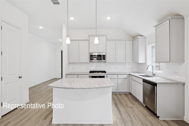 kitchen featuring sink, a center island, appliances with stainless steel finishes, pendant lighting, and white cabinets