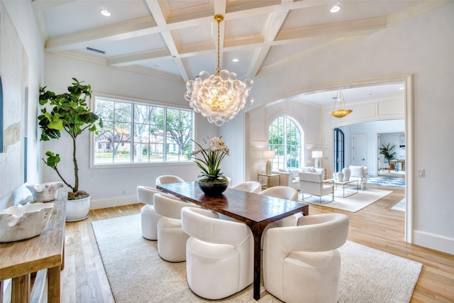 dining area featuring arched walkways, coffered ceiling, wood finished floors, and an inviting chandelier