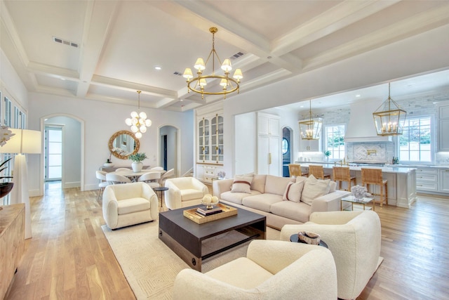 living area with light wood-type flooring, arched walkways, visible vents, and an inviting chandelier