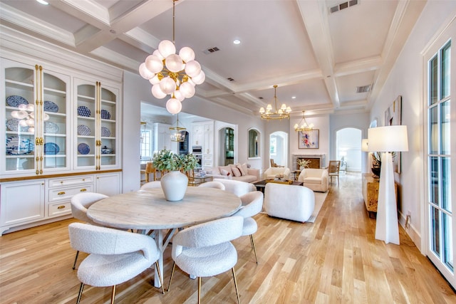 dining room with light wood-style floors, visible vents, arched walkways, and a notable chandelier