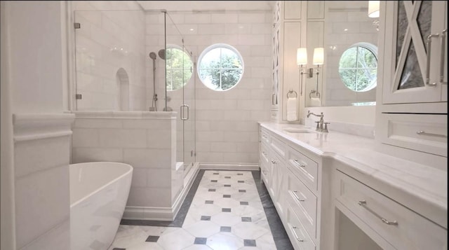 full bath featuring a healthy amount of sunlight, a shower stall, tile walls, and vanity