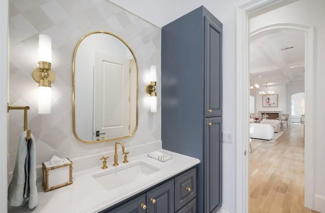 bathroom featuring visible vents, vanity, wood finished floors, coffered ceiling, and beamed ceiling