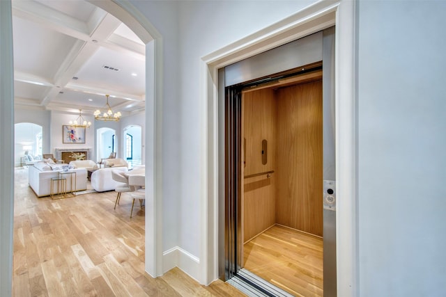 corridor with visible vents, coffered ceiling, arched walkways, beamed ceiling, and light wood-style floors