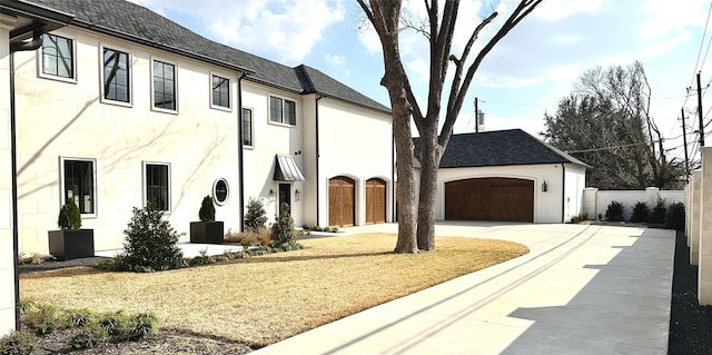 view of front of home with a shingled roof, driveway, a garage, and fence