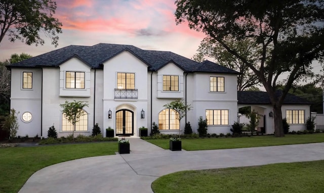 view of front facade featuring french doors, a front yard, and stucco siding