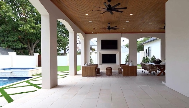 view of patio featuring ceiling fan, outdoor dining area, fence, and an outdoor fireplace